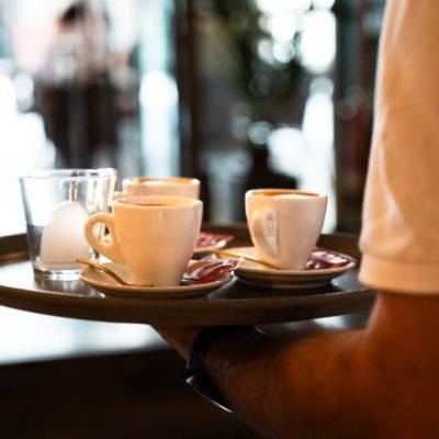 Close-up of a tray with coffees held by a waiter.